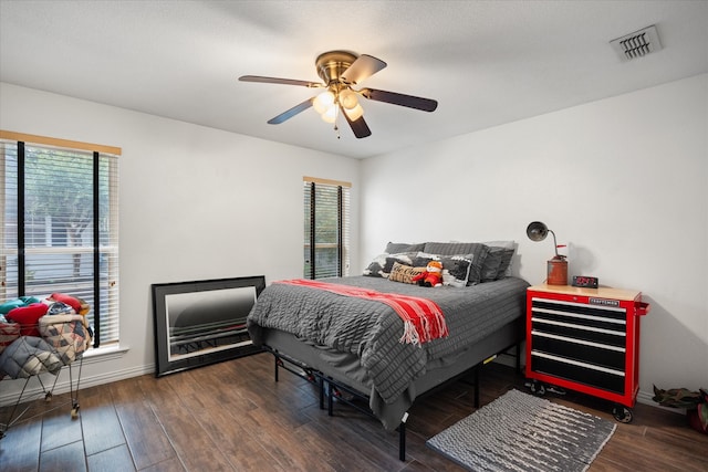 bedroom with dark wood-type flooring, multiple windows, and ceiling fan