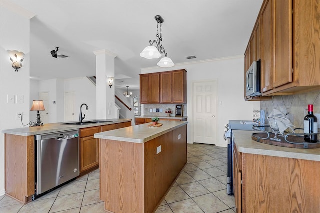 kitchen featuring hanging light fixtures, sink, appliances with stainless steel finishes, tasteful backsplash, and a kitchen island