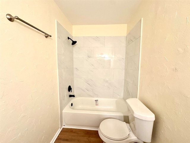 bathroom with hardwood / wood-style floors, tiled shower / bath, and toilet