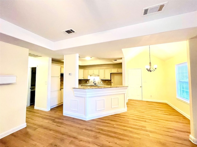 kitchen featuring decorative backsplash, light wood-type flooring, a chandelier, white cabinetry, and hanging light fixtures