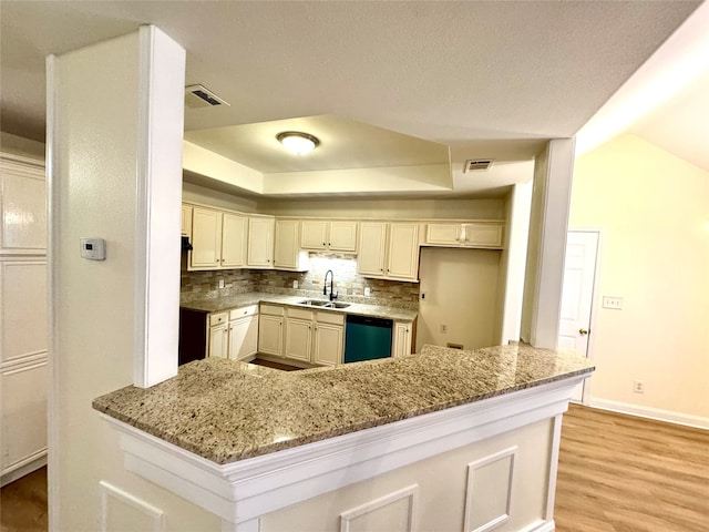 kitchen featuring dishwasher, sink, light stone counters, light hardwood / wood-style flooring, and kitchen peninsula