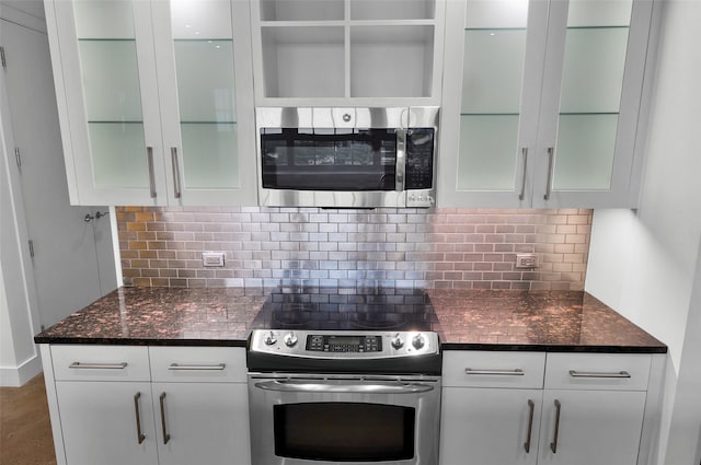 kitchen with dark stone counters, white cabinetry, appliances with stainless steel finishes, and decorative backsplash