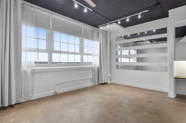 empty room with rail lighting and concrete floors