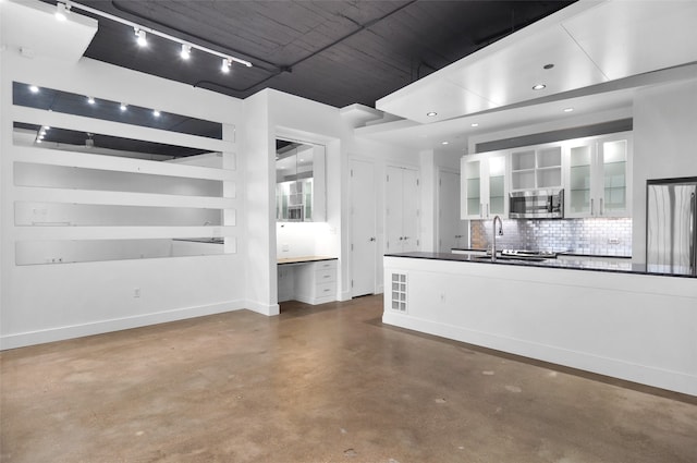 kitchen featuring stainless steel appliances, concrete floors, sink, backsplash, and white cabinetry