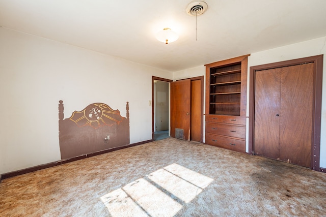 unfurnished bedroom featuring multiple closets and carpet flooring