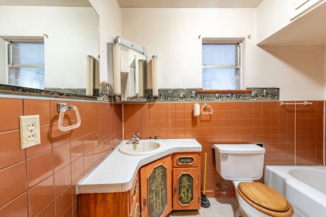 bathroom with tile walls, a bath, vanity, and toilet