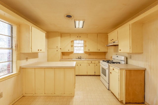 kitchen featuring cream cabinets, white range with gas cooktop, sink, and kitchen peninsula