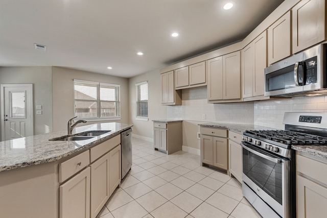 kitchen featuring light tile patterned flooring, appliances with stainless steel finishes, decorative backsplash, sink, and cream cabinetry