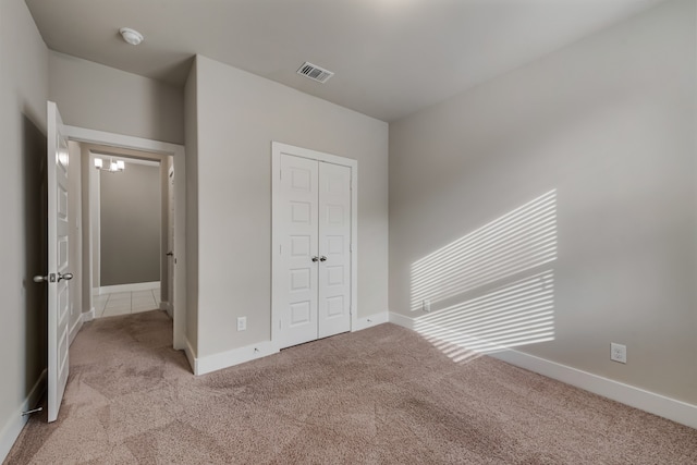 unfurnished bedroom with light carpet and a closet