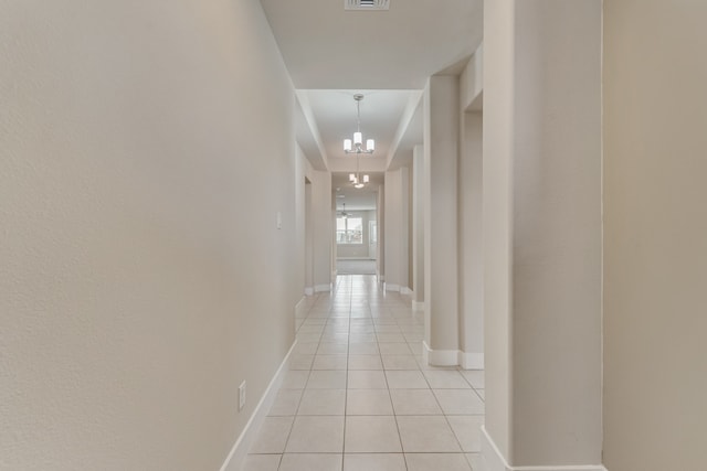 hallway with an inviting chandelier and light tile patterned flooring