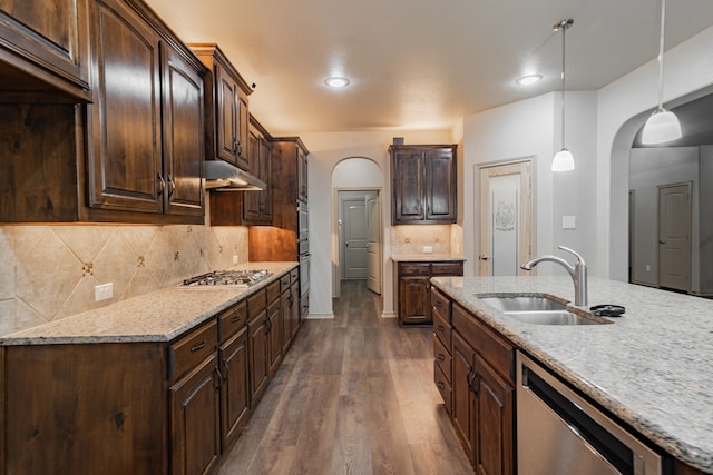 kitchen with appliances with stainless steel finishes, decorative light fixtures, dark brown cabinets, dark hardwood / wood-style flooring, and sink