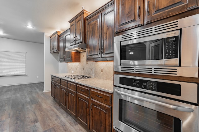 2216 Rosalinda Pass, Fort Worth, TX 76131 - kitchen featuring appliances with stainless steel finishes, under cabinet range hood, dark brown cabinets, backsplash, and light stone counters