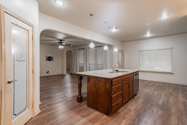 kitchen with dark hardwood / wood-style flooring, hanging light fixtures, stainless steel dishwasher, and an island with sink