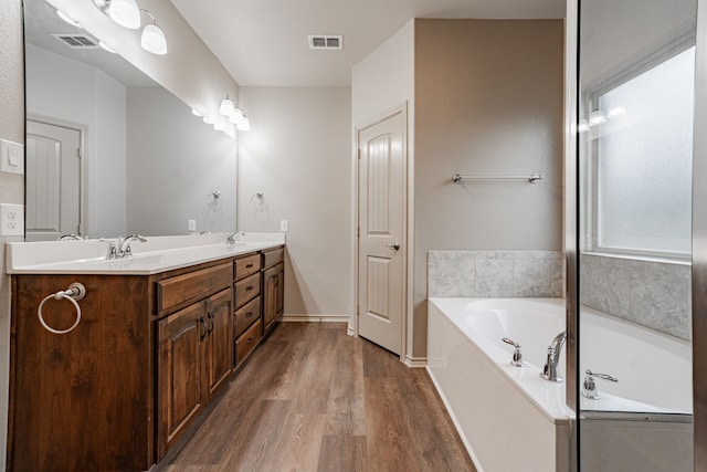 bathroom with hardwood / wood-style floors, vanity, and a tub to relax in