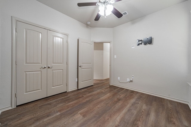 unfurnished bedroom featuring dark hardwood / wood-style flooring, ceiling fan, and a closet