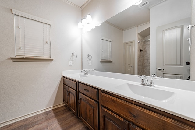 bathroom featuring a tile shower, vanity, hardwood / wood-style flooring, and crown molding