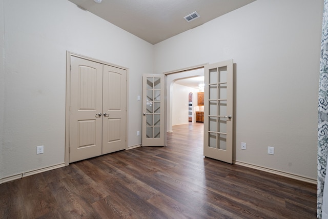 unfurnished bedroom featuring dark hardwood / wood-style floors, a closet, and french doors