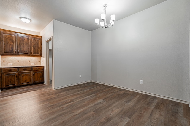 unfurnished dining area with dark hardwood / wood-style floors and an inviting chandelier