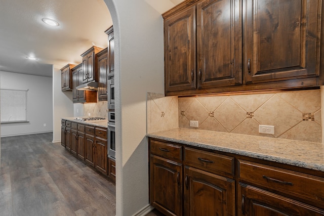 kitchen with dark wood-type flooring, dark brown cabinets, appliances with stainless steel finishes, and tasteful backsplash