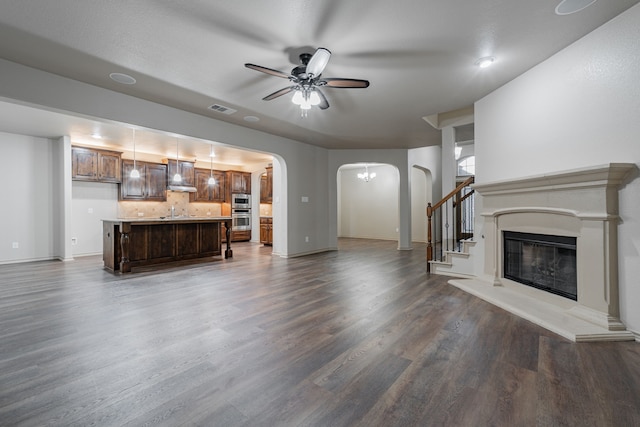 unfurnished living room with dark hardwood / wood-style flooring, ceiling fan, and sink