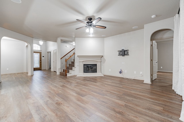 2216 Rosalinda Pass, Fort Worth, TX 76131 - unfurnished living room featuring arched walkways, ceiling fan, light wood finished floors, and a glass covered fireplace