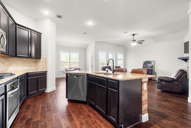 kitchen featuring stainless steel appliances, sink, a kitchen island with sink, and dark hardwood / wood-style flooring