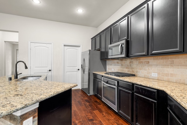 kitchen with appliances with stainless steel finishes, sink, light stone counters, and dark hardwood / wood-style flooring