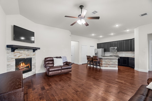 living room featuring ceiling fan, dark hardwood / wood-style floors, and a fireplace