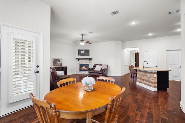 dining area with ceiling fan, sink, dark hardwood / wood-style floors, and a fireplace