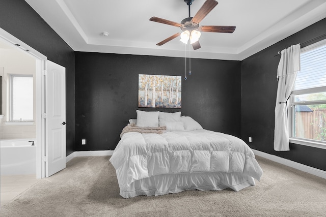 carpeted bedroom with ceiling fan and a raised ceiling