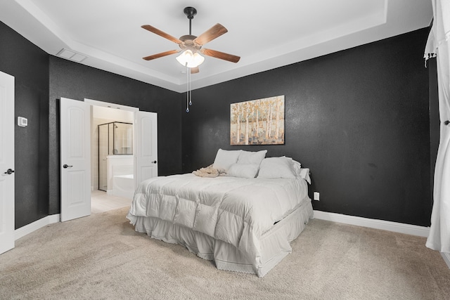 bedroom featuring ensuite bathroom, light carpet, ceiling fan, and a tray ceiling