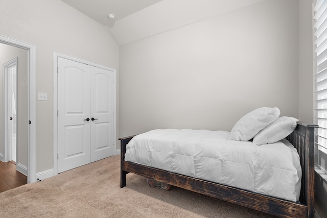 carpeted bedroom featuring lofted ceiling and a closet