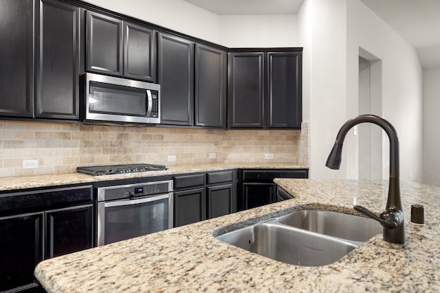 kitchen with light stone countertops, sink, appliances with stainless steel finishes, and tasteful backsplash