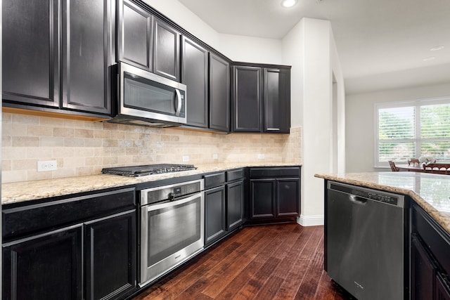 kitchen featuring light stone countertops, stainless steel appliances, backsplash, and dark hardwood / wood-style flooring