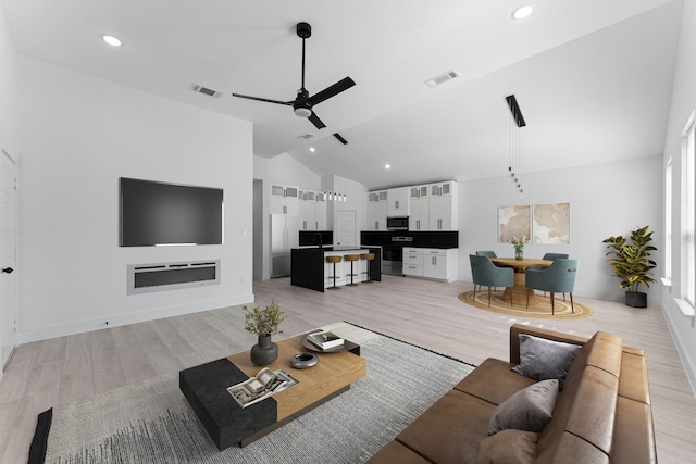 living room with ceiling fan, high vaulted ceiling, and light hardwood / wood-style flooring