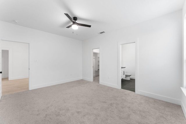 unfurnished bedroom featuring light colored carpet, ceiling fan, and ensuite bathroom