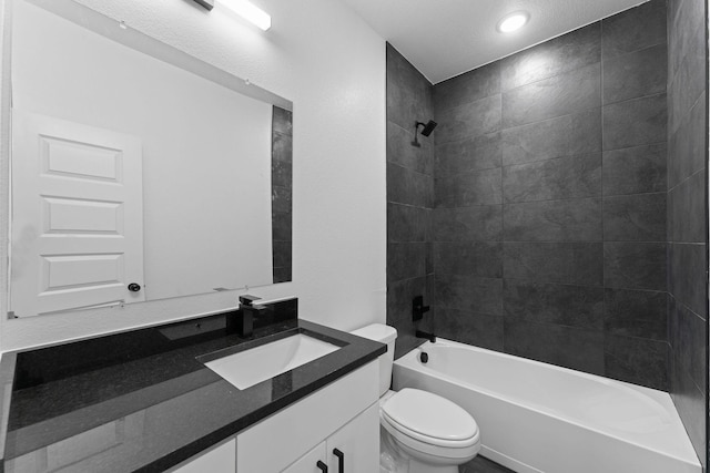 full bathroom with tiled shower / bath, vanity, a textured ceiling, and toilet