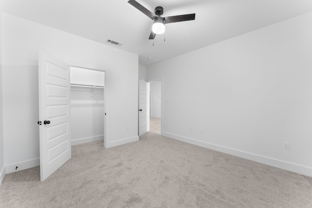 unfurnished bedroom with ceiling fan, light colored carpet, and a closet