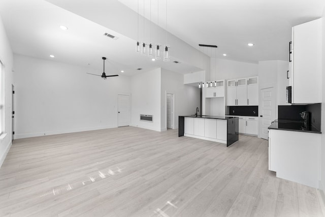 kitchen featuring pendant lighting, light hardwood / wood-style flooring, ceiling fan, white cabinetry, and a kitchen island with sink