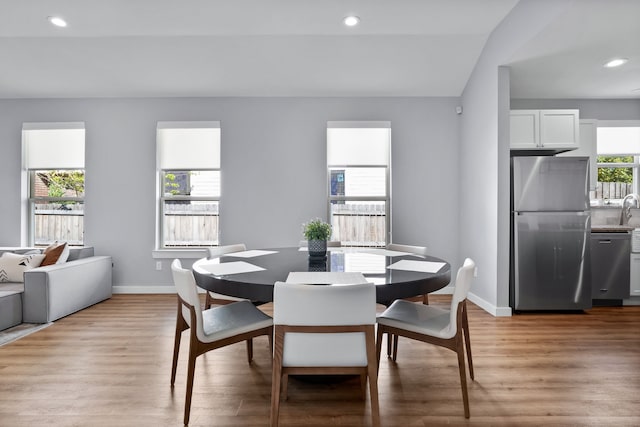 dining area featuring light wood-type flooring and lofted ceiling