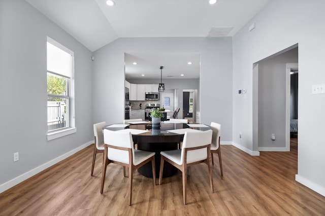 dining room featuring light wood-type flooring and lofted ceiling