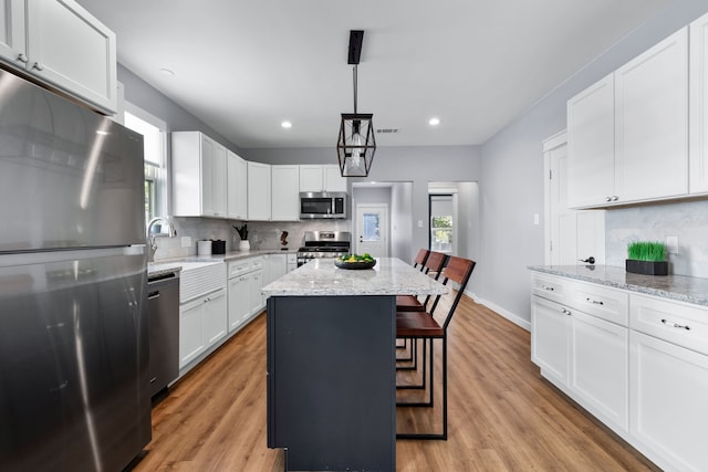 kitchen featuring white cabinetry, appliances with stainless steel finishes, a healthy amount of sunlight, and a kitchen island