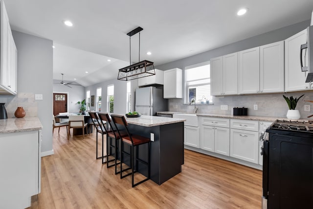 kitchen featuring white cabinets, a healthy amount of sunlight, black range, and stainless steel fridge