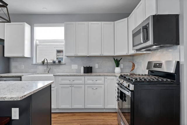 kitchen featuring sink, appliances with stainless steel finishes, light hardwood / wood-style flooring, white cabinets, and decorative backsplash