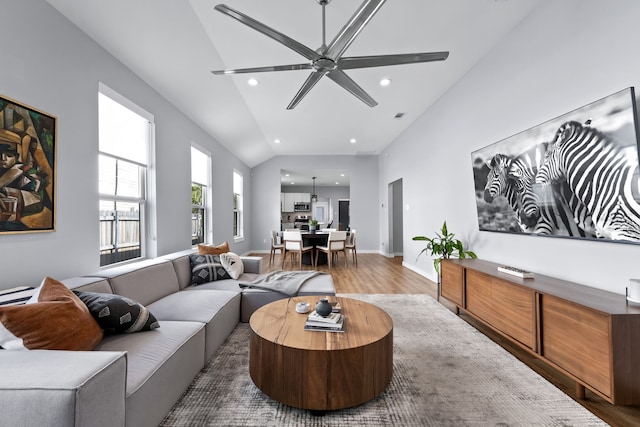 living room with hardwood / wood-style flooring, ceiling fan, and vaulted ceiling