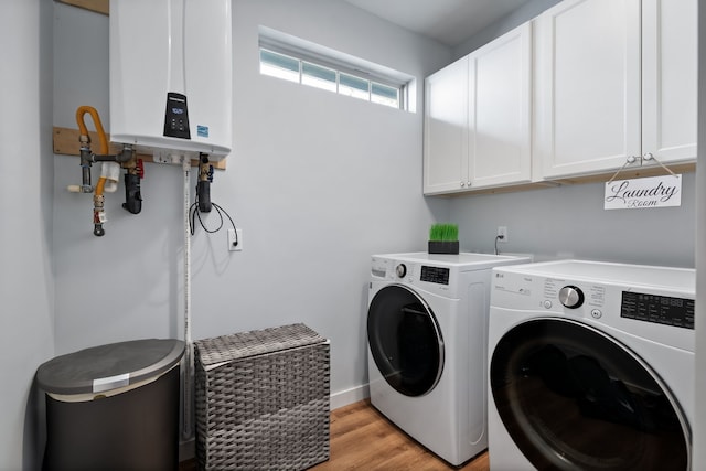 laundry room with cabinets, tankless water heater, light wood-type flooring, and separate washer and dryer