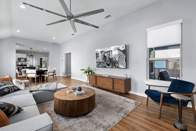 living room featuring hardwood / wood-style flooring, ceiling fan, and vaulted ceiling