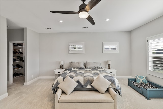 carpeted bedroom with ceiling fan, a spacious closet, and multiple windows