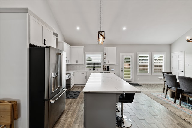 kitchen featuring high end refrigerator, white cabinetry, a kitchen island, and lofted ceiling