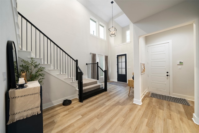 foyer entrance featuring a high ceiling, a notable chandelier, and light hardwood / wood-style floors